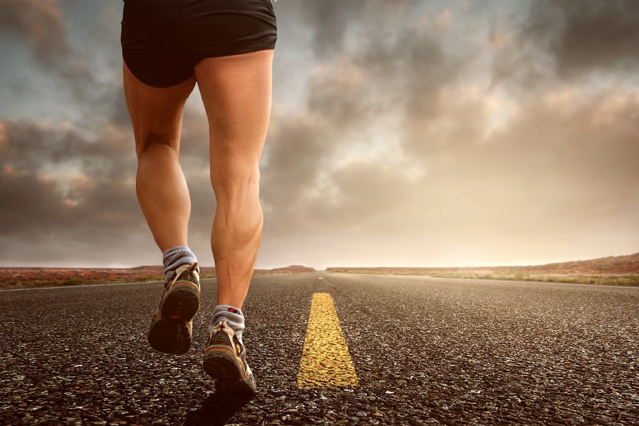 Runners legs on a road during a sunset, symbolizing endurance and outdoor fitness training.